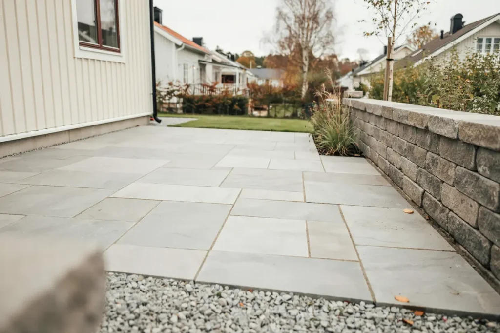 ny stenlagd uteplats med mur vid villa i romberga